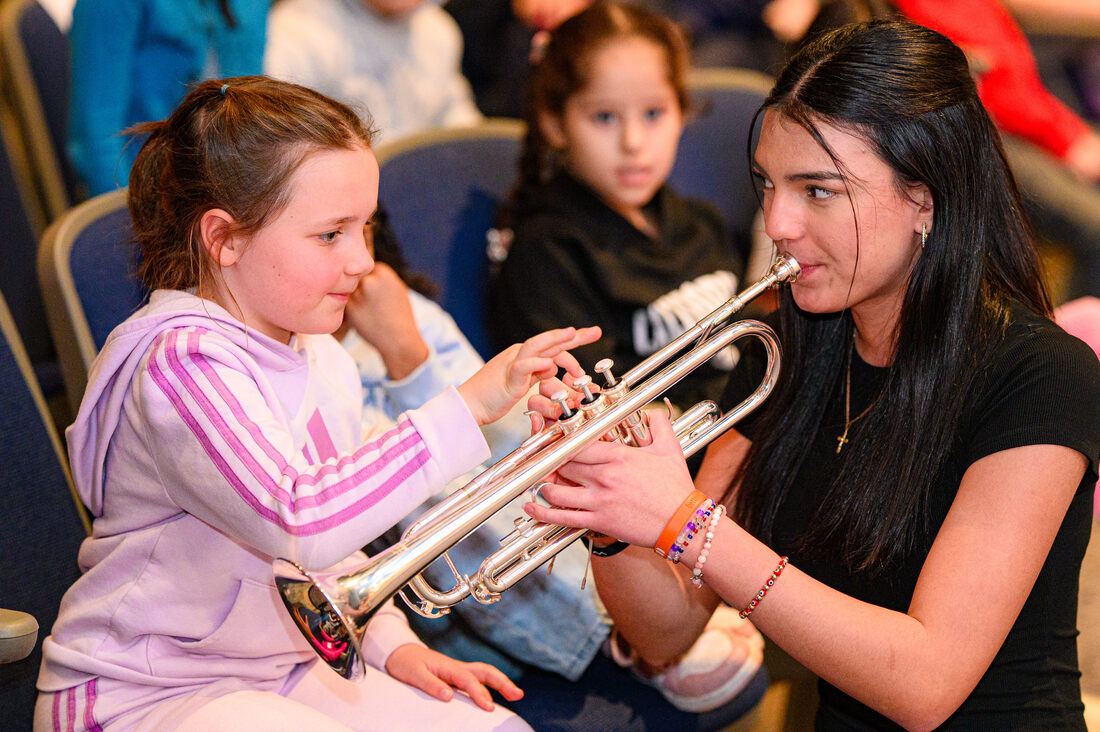 a child listens to a musician play an instrument