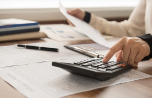 a person uses investment information and a calculator to work on financial planning